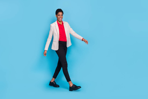 Full length profile portrait of confident person walking wear blazer isolated on blue color background. - 写真・画像