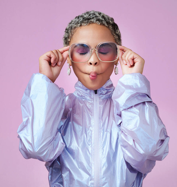 Fashion, beauty and lips with a black woman or model in sunglasses pouting in studio on a pink background. Trendy, style and edgy with an attractive, goofy female posing in contemporary clothes. - 写真・画像