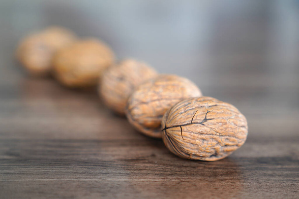 Five walnuts in a row crossed on dark walnut table background - Foto, Imagen