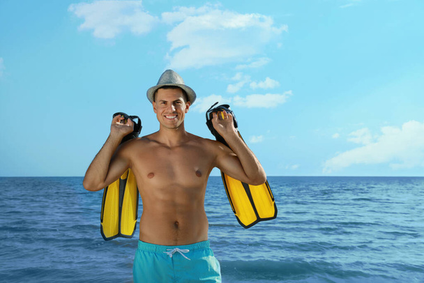Happy man with flippers near sea on beach - Foto, imagen