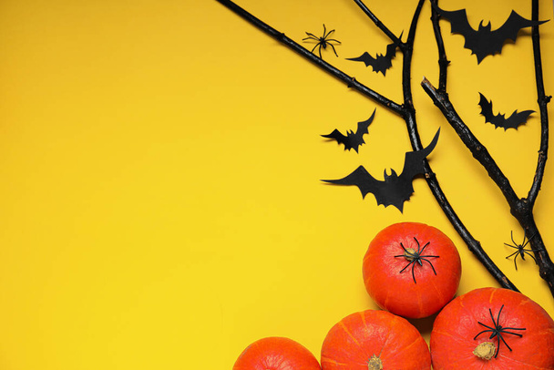 Flat lay composition with black branches, paper bats and pumpkins on yellow background, space for text. Halloween celebration - 写真・画像