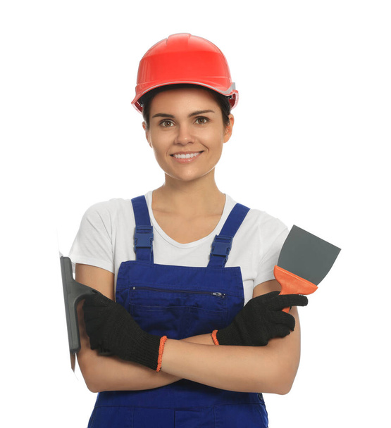 Professional worker with putty knives in hard hat on white background - Foto, afbeelding