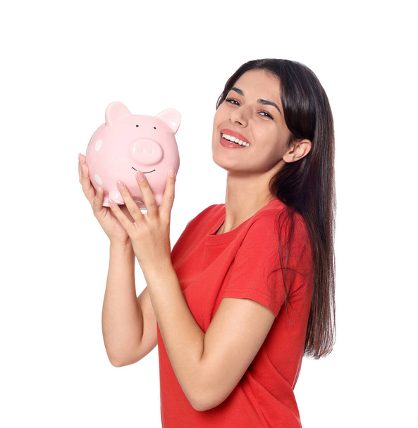 Happy young woman with piggy bank on white background - Foto, afbeelding