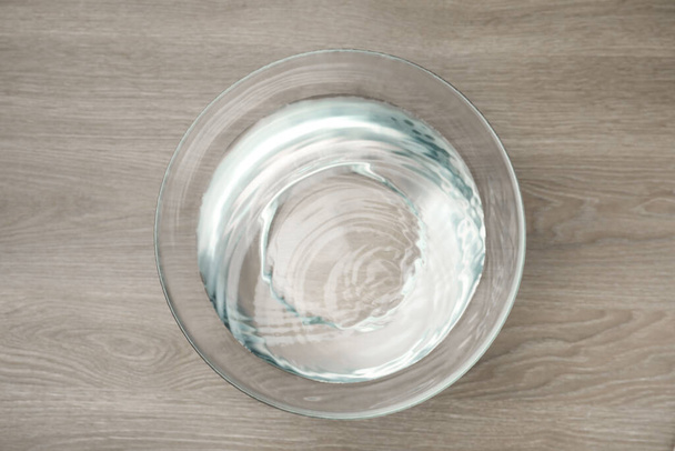 Glasschale mit Wasser auf Holztisch, Draufsicht - Foto, Bild