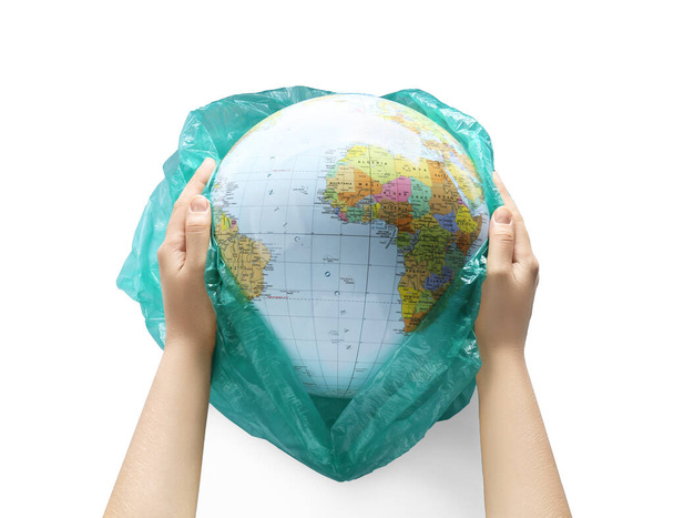 Woman holding globe in plastic bag on white background, closeup. Environmental protection concept - Φωτογραφία, εικόνα
