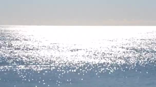 要旨ぼやけた背景海の波の青い表面に輝く太陽の白い反射のスポット。晴れた日の海。自然なぼやけたボケのテクスチャの背景。シームレスなループ。 - 映像、動画