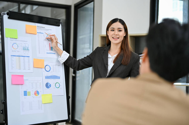 Professionele Aziatische zakenvrouw of vrouwelijke financiële analist presenteren haar financiële gegevens informatie aan haar team in de vergadering. - Foto, afbeelding