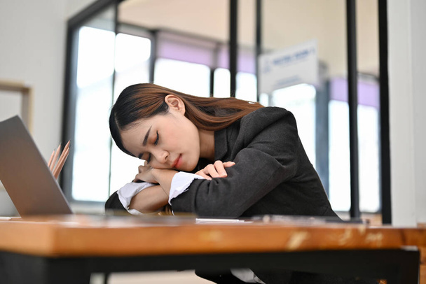 Stanco, esausto giovane donna d'affari asiatica o impiegato donna caduto testa sulle mani, addormentarsi alla sua scrivania, sonnecchiare sul suo posto di lavoro. - Foto, immagini