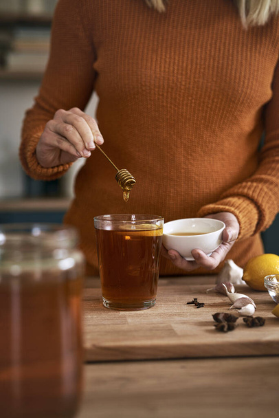 Közelkép kaukázusi nő készít őszi tea mézzel - Fotó, kép