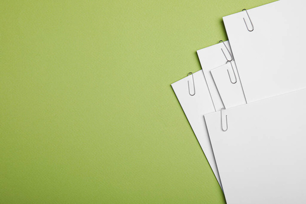 Sheets of paper with clips on light green background, top view. Space for text - Foto, Imagen
