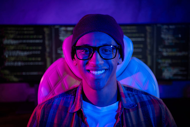 Porträt von fröhlichen intelligenten Hacker Kerl sitzt Stuhl zahmes Lächeln Nacht Büro-Workstation drinnen. - Foto, Bild