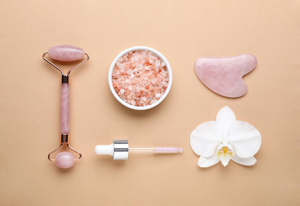Flat lay composition with gua sha stone and face roller on beige background - Valokuva, kuva