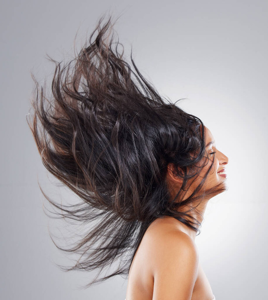 Loving her perfect hair day. an attractive young woman posing in studio against a grey background - Photo, Image