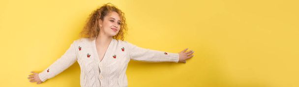 Young cheerful girl smiling at the camera while standing on a yellow background close-up. - Photo, Image