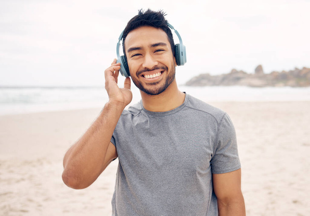 I feel less stressed when Im outdoors. Portrait of a sporty young man wearing headphones while exercising on the beach - Fotó, kép