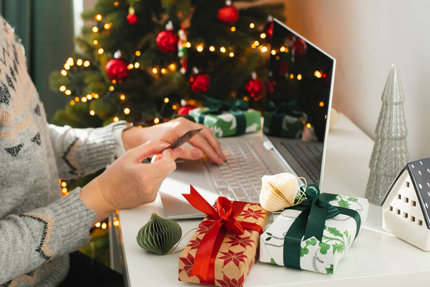 Female hand holding card. Woman using laptop. Christmas online shopping concept. Winter holidays sales - Photo, Image