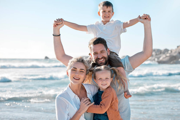 Portrait of a happy caucasian family of four on vacation by the sea. Children enjoying a getaway with their parents on bright summer day, smiling family relaxed against a bright copyspace background. - Фото, изображение