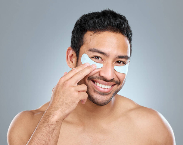 A few minutes of pampering can do wonders. a man wearing under-eye gel patches while posing against a grey background - 写真・画像