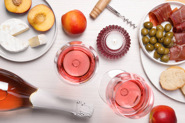 Delicious rose wine and snacks on white wooden table, flat lay - Φωτογραφία, εικόνα