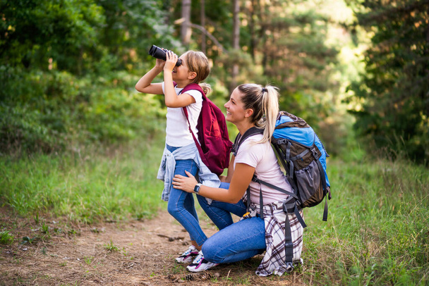 Mother and daughter using binoculars and enjoy hiking together. - Photo, Image