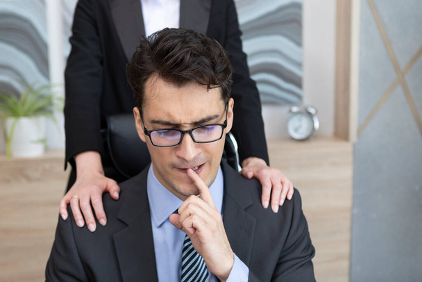 Ein junger gutaussehender Mann fühlt sich unwohl, weil seine Chefin sich im Büro unangemessen benimmt. Belästigung am Arbeitsplatz - Foto, Bild
