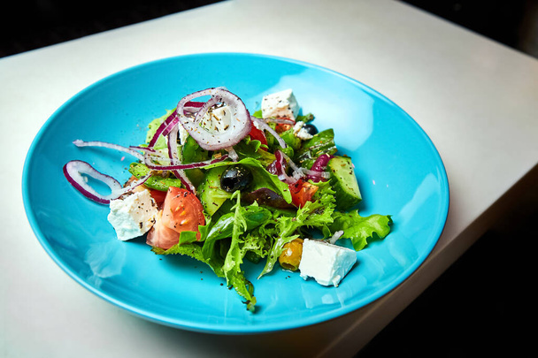 Görög saláta zöldségekkel, feta sajttal, olajbogyóval és olívaolajjal. Közelkép, szelektív fókusz - Fotó, kép