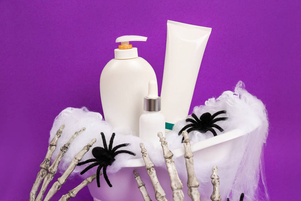 Halloween produtos cosméticos na banheira em fundo roxo, loção, óleo essencial e creme cosmético, modelo - Foto, Imagem