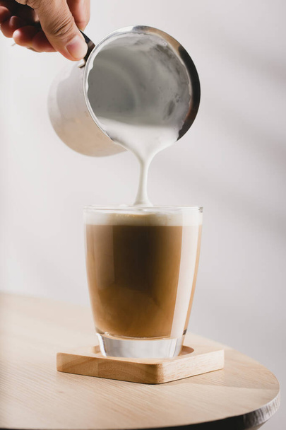 Cappuccino ve skleněném šálku na dřevěném stole, káva a pěnové mléko - Fotografie, Obrázek