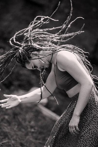 Beautiful girl with dreadlocks, dressed hippie style,poses outdoors. - Фото, изображение