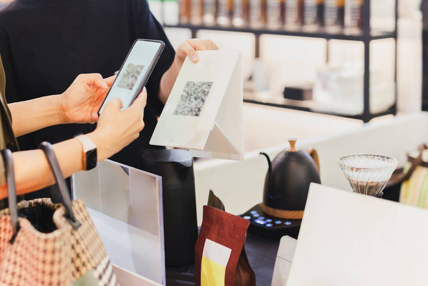 Femme client payant par balayage de code QR sur téléphone mobile à la boutique - Photo, image