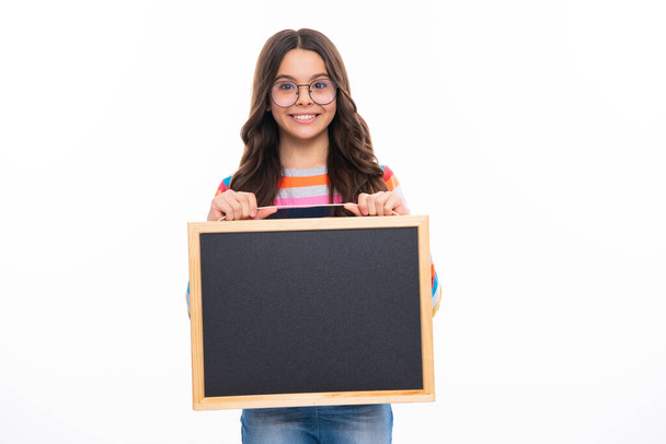 Adolescente enfant tenant tableau noir, isolée sur un fond blanc. Fille heureuse visage, émotions positives et souriantes - Photo, image