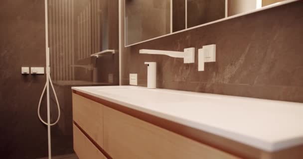 Minimalistický interiér v hnědých barvách s koupelnovým příslušenstvím, zrcadlem a sprchovým koutem, vanou moderní design. Luxusní útulný bílý byt. Moderní koupelna s jednoduchým designem. - Záběry, video