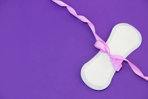 white women's hygienic daily pad and pink bow on a purple background - Photo, Image