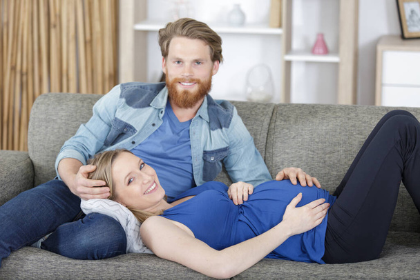 pregnant woman layed on partners lap on the sofa - Foto, Bild