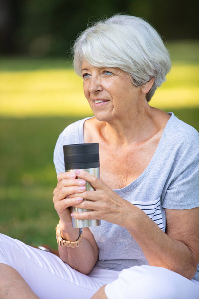 senior woman holding insulated cup in the park - Fotografie, Obrázek