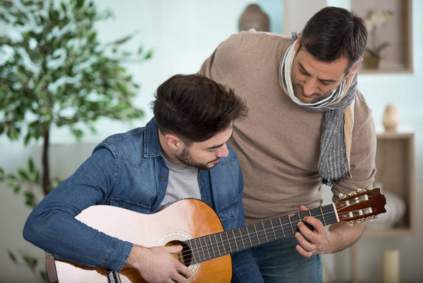 father teaches his son to play the guitar - Foto, imagen