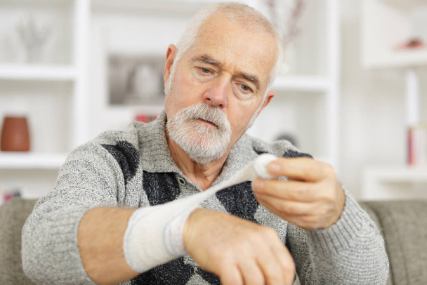 man is bandaging his own wrist - Zdjęcie, obraz