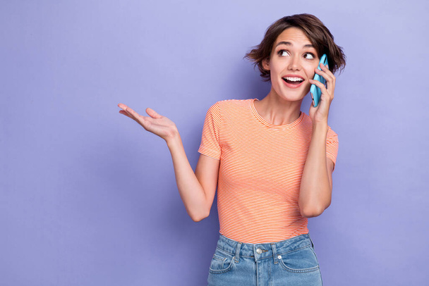 Photo of excited lady speak telephone interested look empty space dressed striped stylish clothes isolated on purple color background. - Fotografie, Obrázek