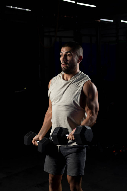 latynoski mężczyzna robi biceps praca w siłowni z dwoma hantlami - Zdjęcie, obraz