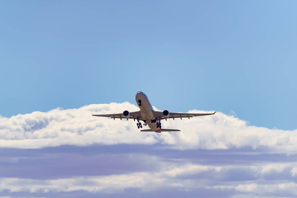 Крупный самолет набирает высоту к облакам после взлета с земли - Фото, изображение