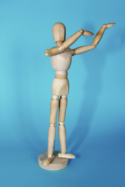 yellow wooden mannequin poses and gestures with his hands on a blue background - Photo, Image