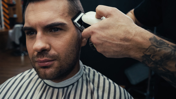 Tatuato barbiere taglio di capelli del cliente in parrucchiere cape in salone  - Foto, immagini