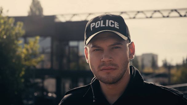 joven policía con gorra con letras policiales y uniforme mirando a la cámara - Foto, Imagen