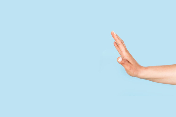 Vrouw hand doen stop teken op een lichtblauwe achtergrond met kopieerruimte - Foto, afbeelding