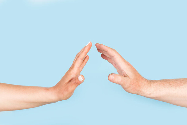 Vrouw en man handen doen stop gebaar op een lichtblauwe achtergrond met kopieerruimte - Foto, afbeelding