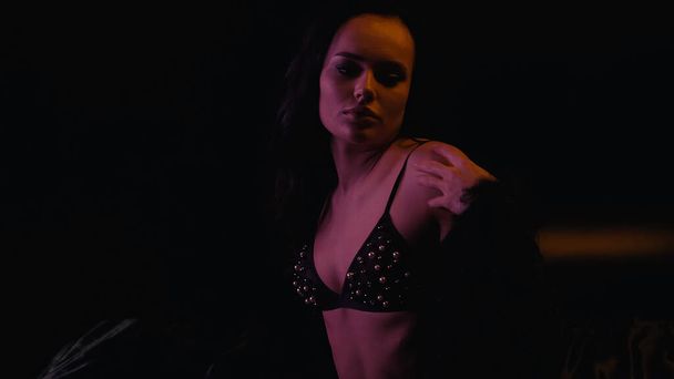 Sensual brunette woman in bra looking away on black background  - Фото, изображение