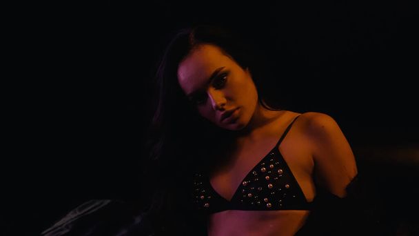 Sexy woman in bra looking at camera on black background  - Foto, Imagen