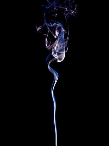 Un sottile flusso di fumo blu e bianco sale dolcemente verso l'alto sullo sfondo nero - Foto, immagini