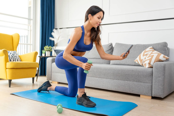 Woman exercising at home. Workout, home fitness concept with online tutorials - Photo, Image