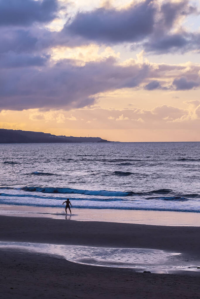 Man die surft bij zonsondergang op het Las Canteras Beach in Las Palmas - Foto, afbeelding